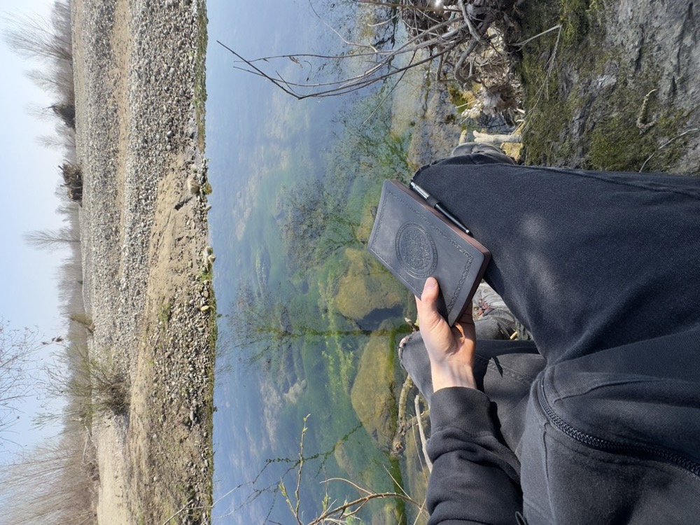 Seduto sulla riva di un fiume con il quaderno in mano